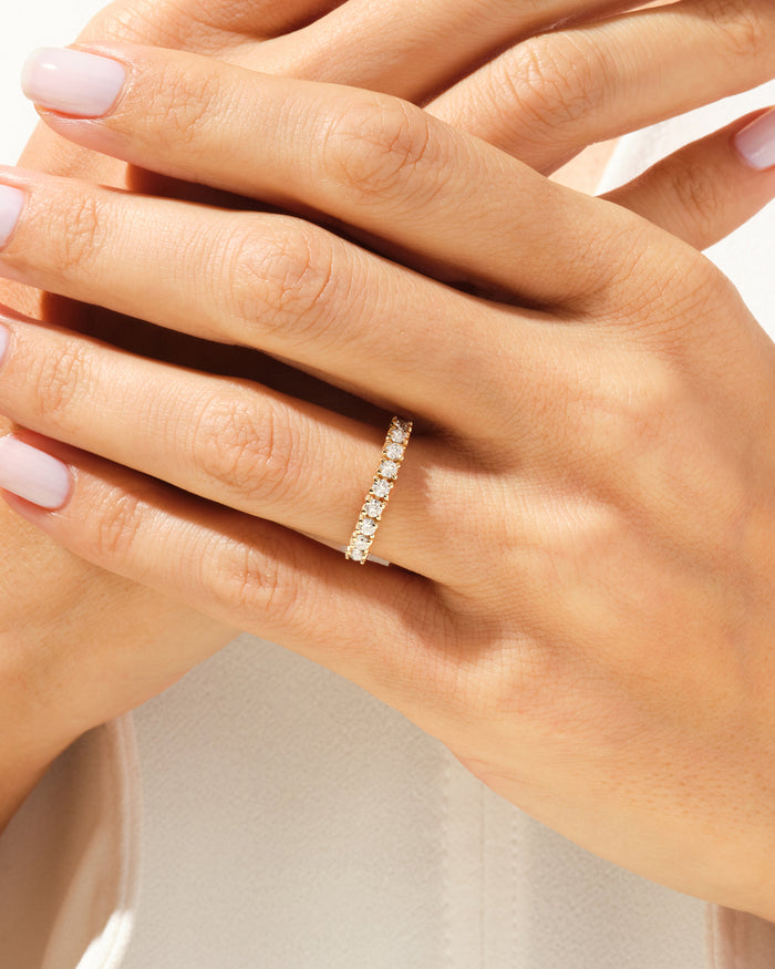Nine stone moissanite basket band in yellow gold worn on a hand