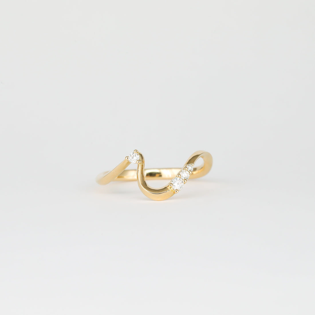 Round lab grown diamond curved wave wedding band in yellow gold, front view