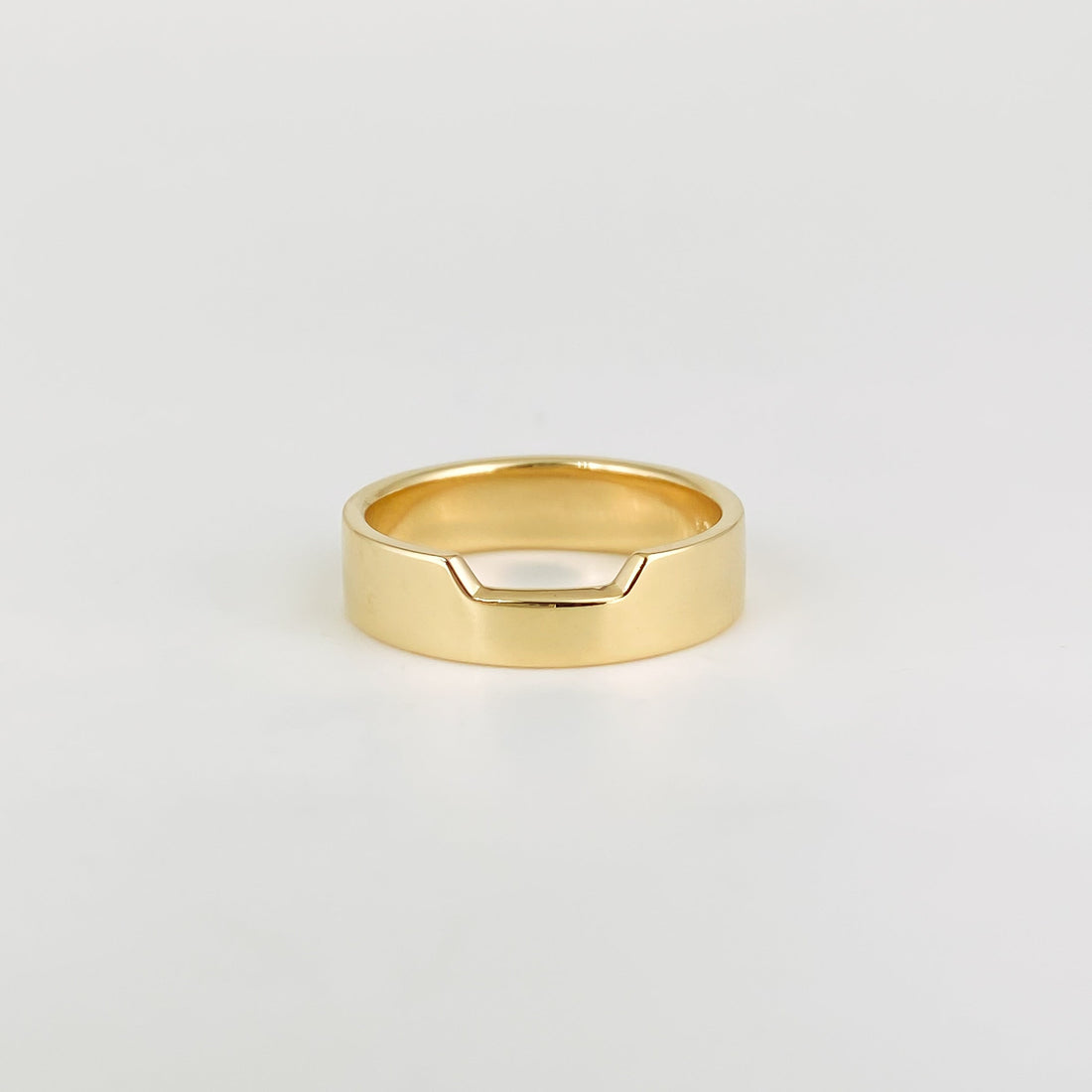 Plain wide contour wedding band with a notched top edge in yellow gold, front view