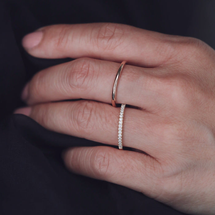Plain slim round wedding band worn next to a stone set band
