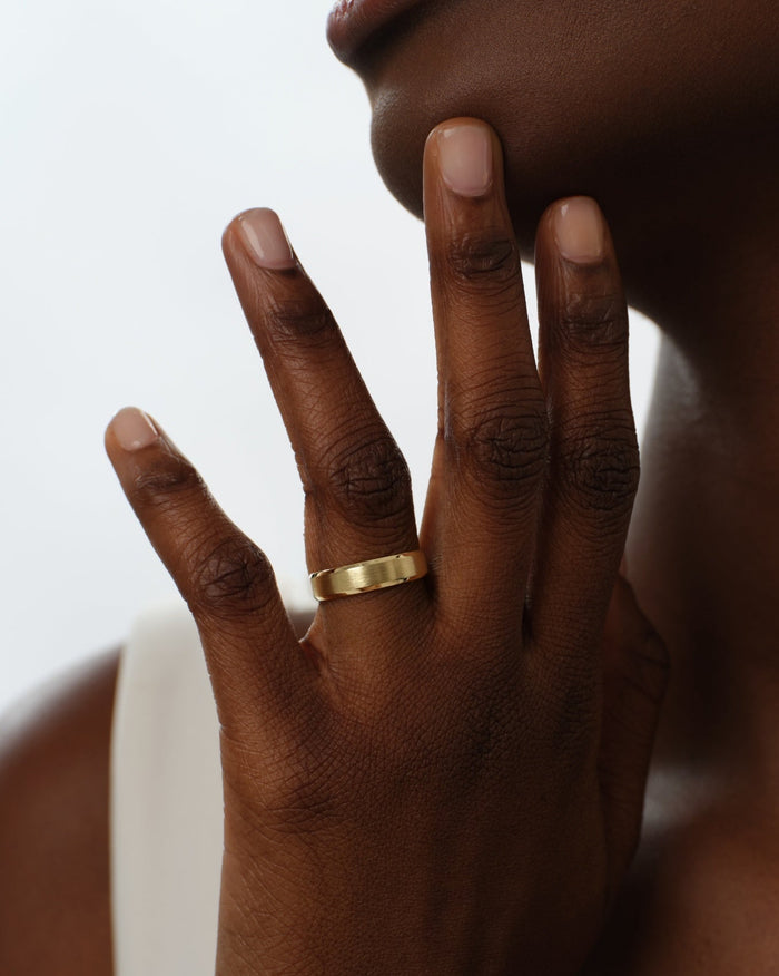 Beveled edge matte brushed gold wedding band worn on a hand