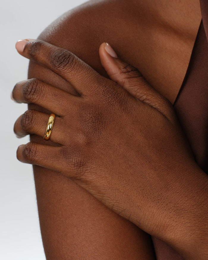 Classic dome gold wedding band worn on a hand
