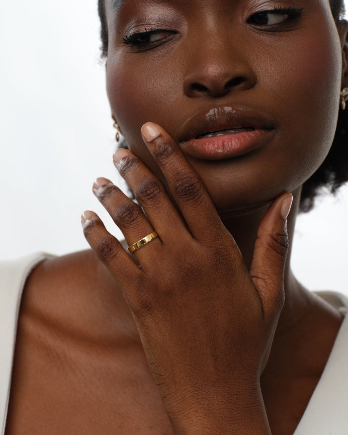 Classic flat gold wedding band worn on a hand