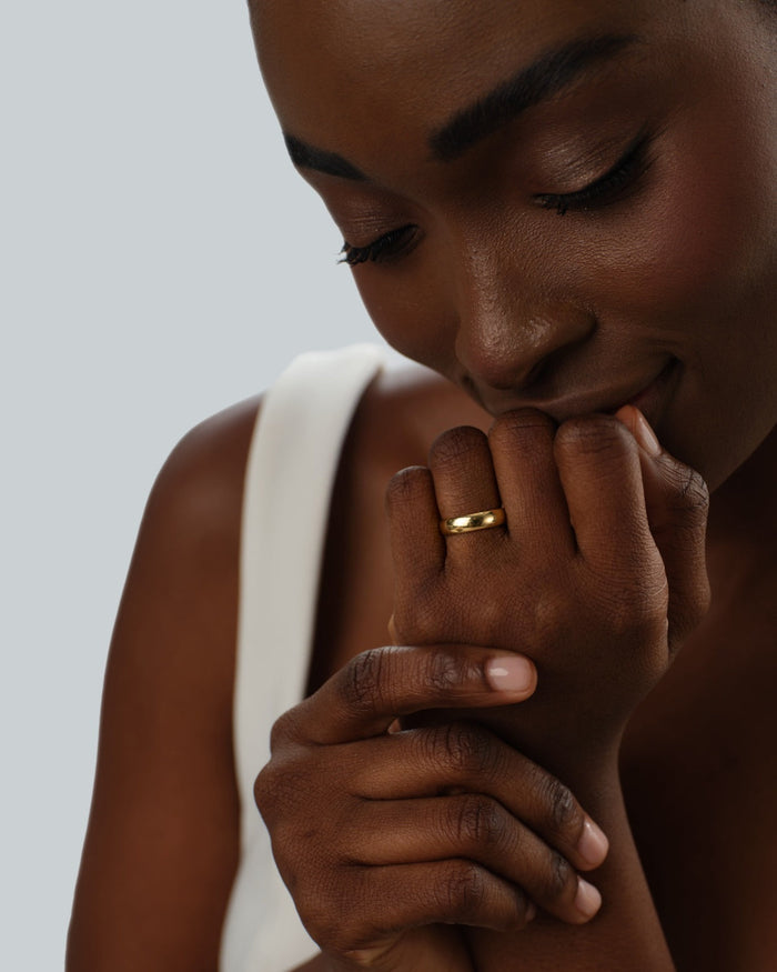 Classic dome gold wedding band worn on a hand