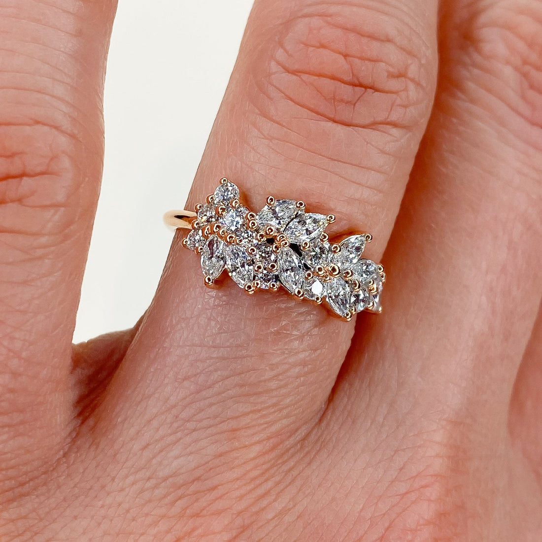 Round and marquise lab grown diamond cluster wedding band in rose gold worn on a finger