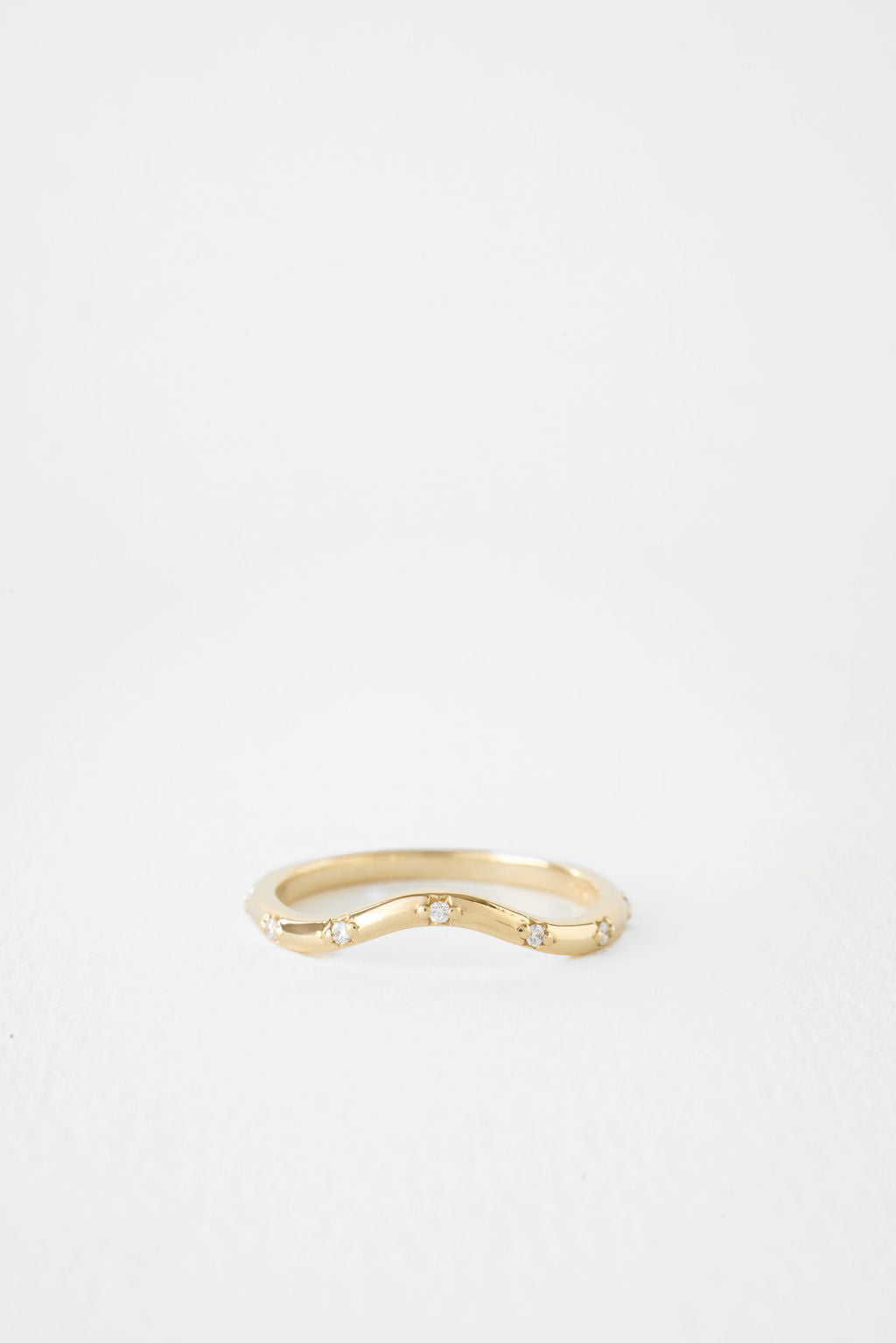 Round lab grown diamond curved flush set wedding band in yellow gold, front view