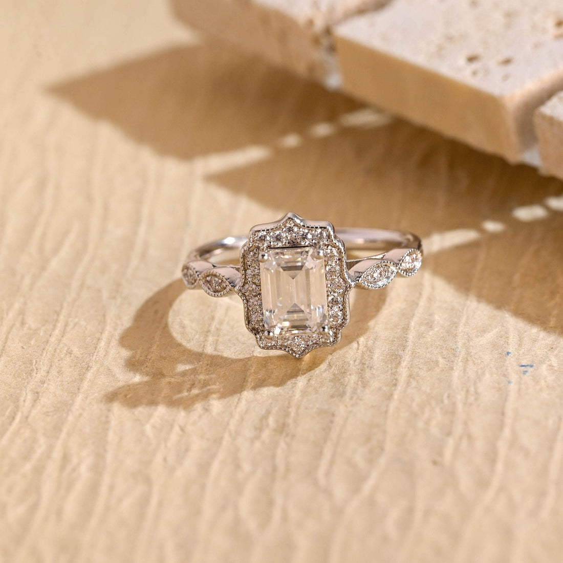 Emerald cut moissanite vintage halo engagement ring with milgrain edges and marquise shaped band details in white gold