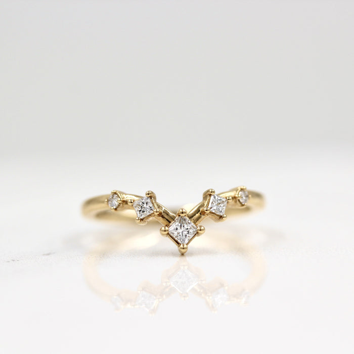 Princess and round moissanite curved V wedding band in yellow gold, front view