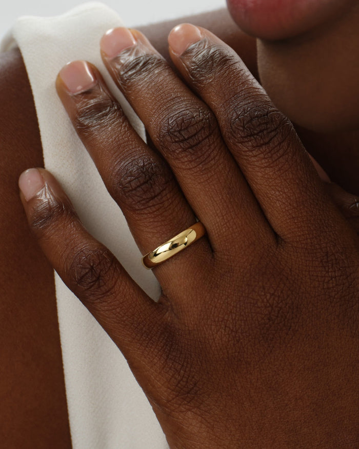 5mm polished dome wedding band in yellow gold worn on a hand