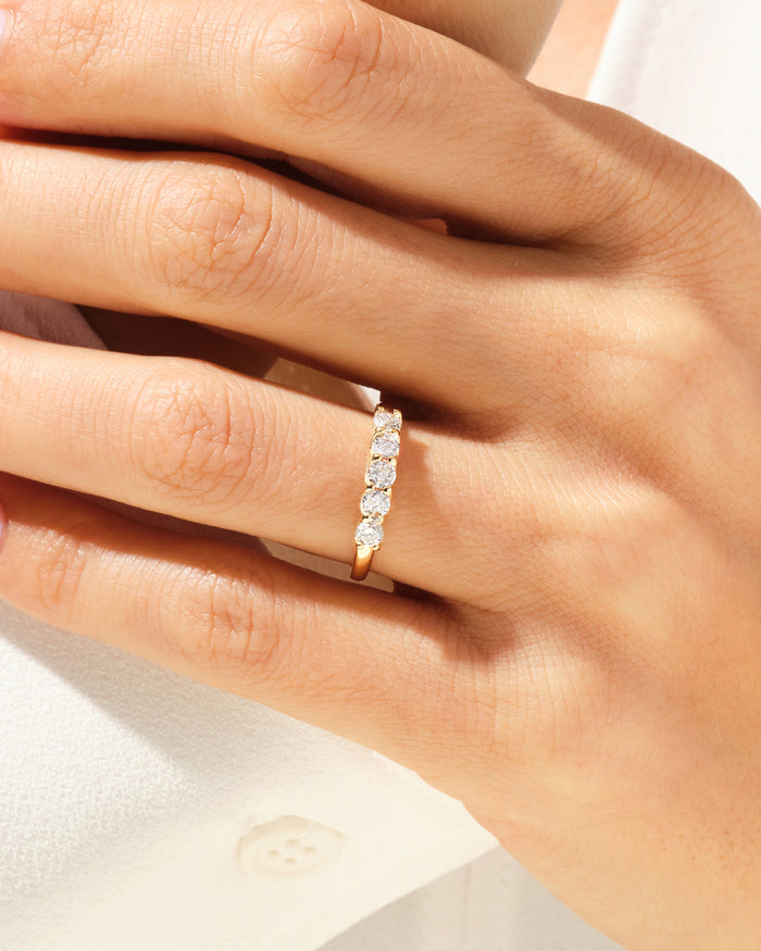 Five stone round moissanite anniversary band worn on the ring finger, close view