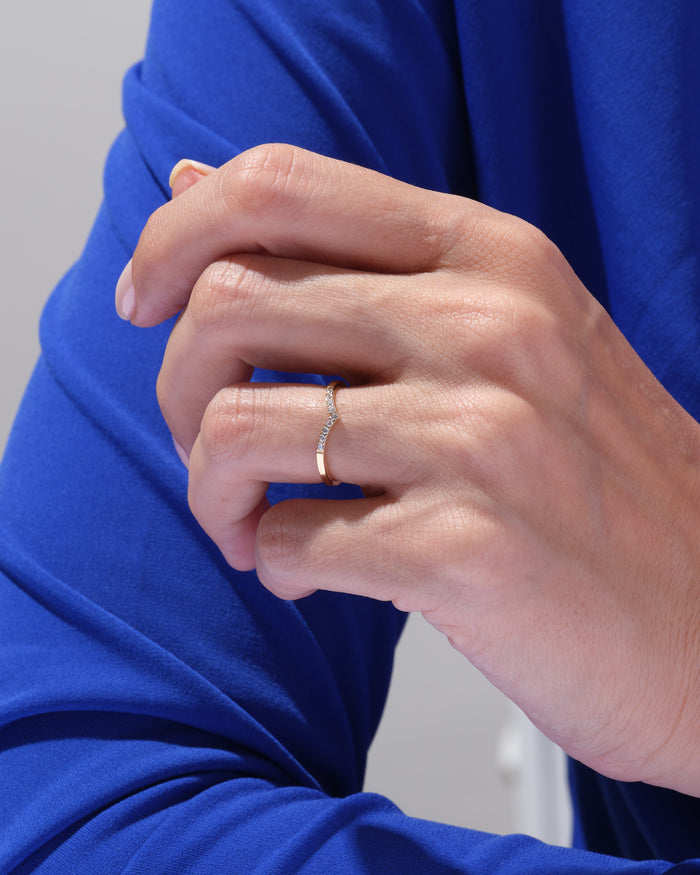 Curved moissanite wedding band worn on a hand