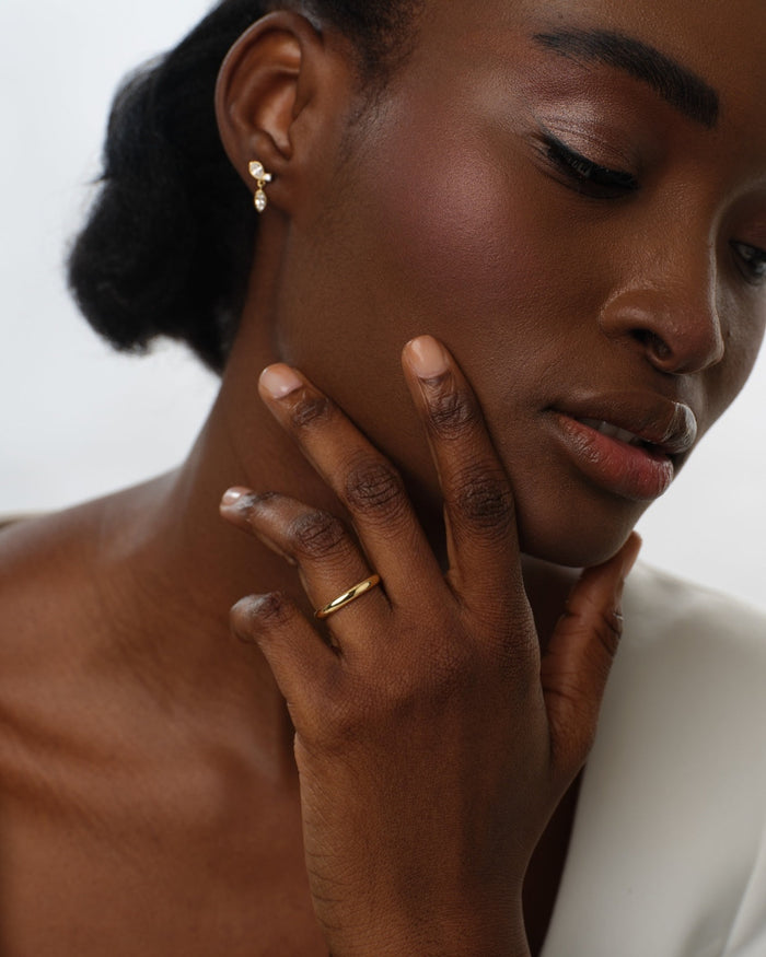 Woman wearing a 3mm classic dome wedding band in yellow gold close to her face