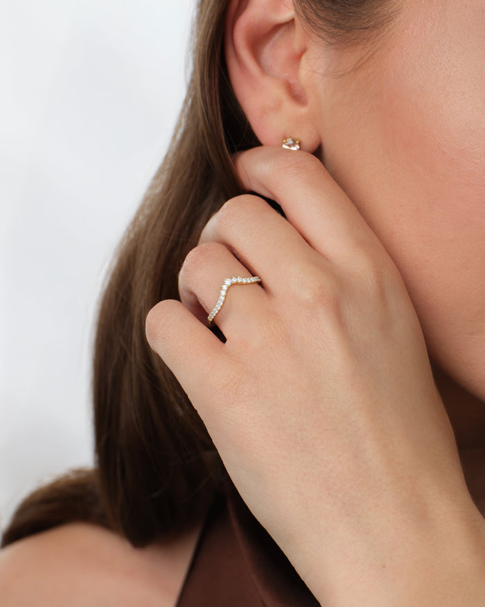 Harmony nesting wedding band worn on a hand raised to the ear