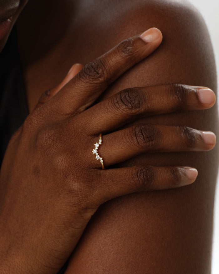 Hand with a round moissanite curved cluster wedding band on the ring finger