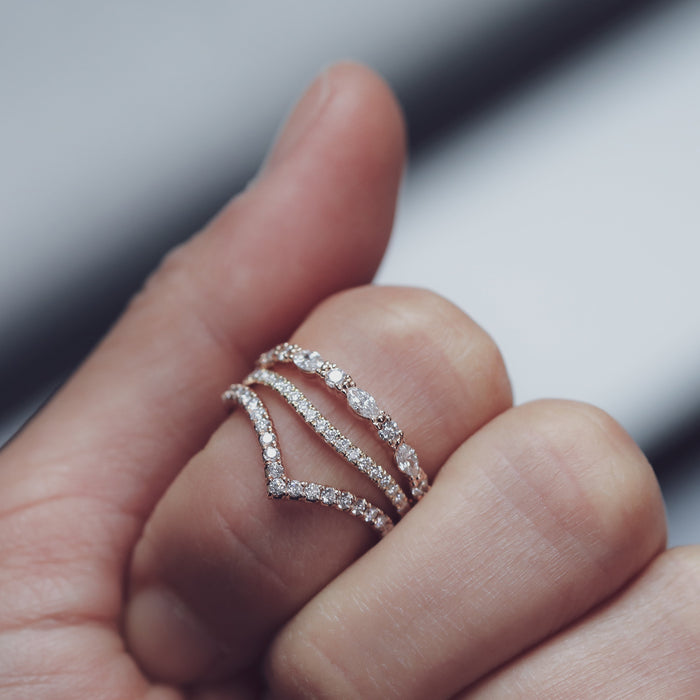Round moissanite chevron band stacked with other bands on a hand