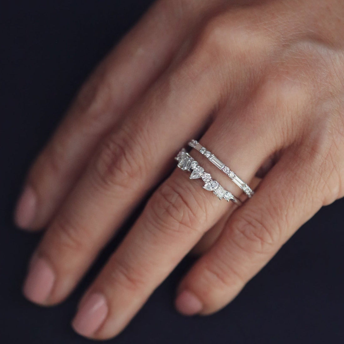Lab grown diamond cluster wedding band in white metal stacked with a slim eternity band on a hand