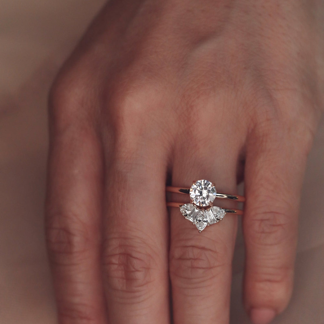 Lab grown diamond five stone crown wedding band in rose gold stacked under a round diamond solitaire ring