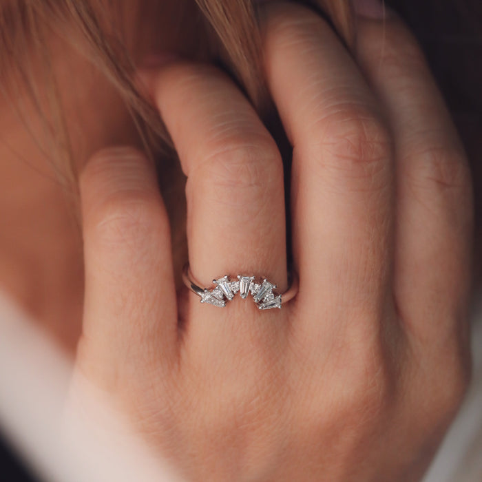 Tapered baguette and round moissanite curved wedding band in white gold worn on a finger