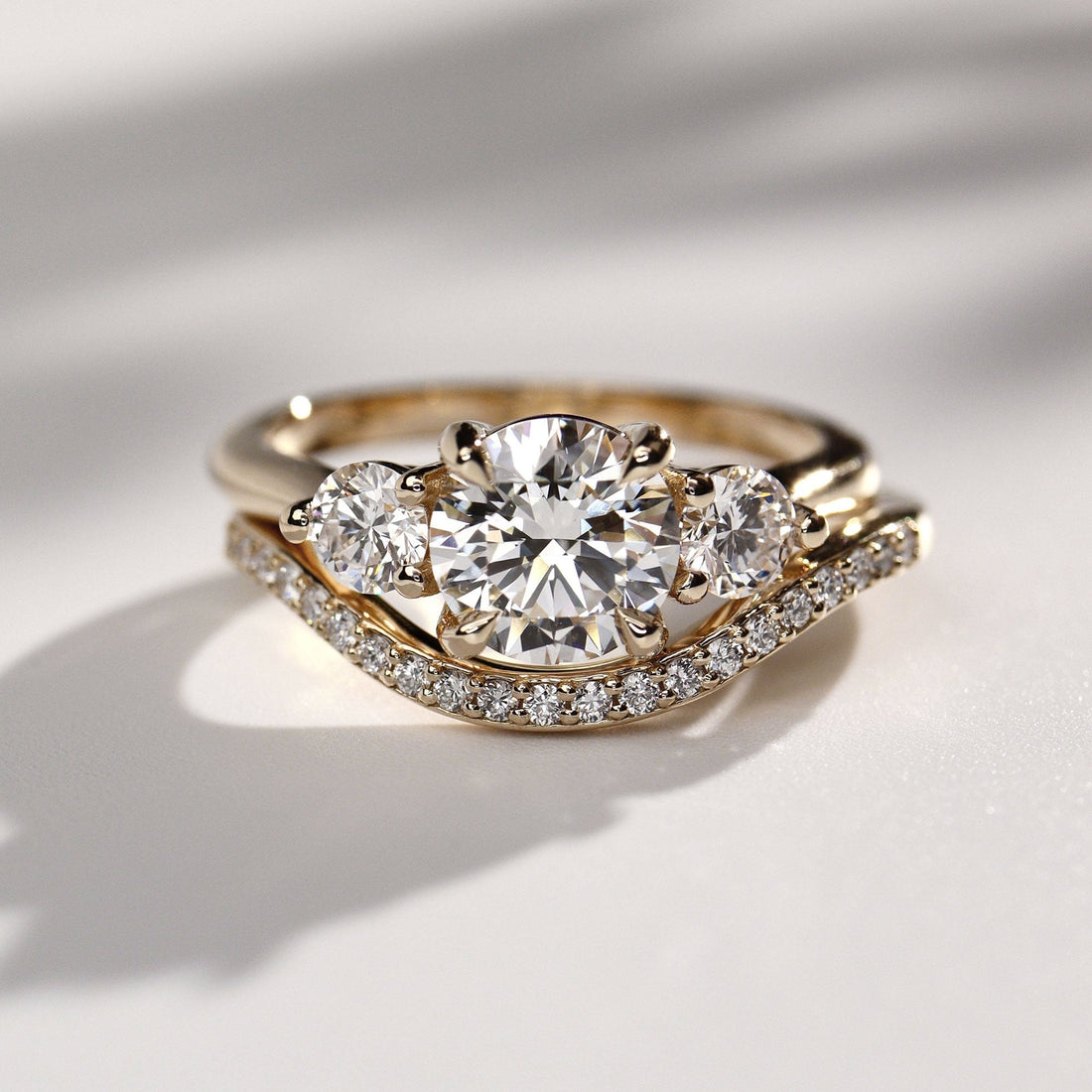 Round brilliant lab grown diamond three stone ring in yellow gold with a curved band, sold separately