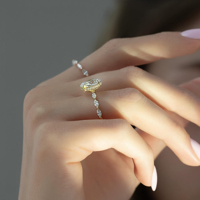 Alternating marquise and round accents along the shoulder of the oval ring