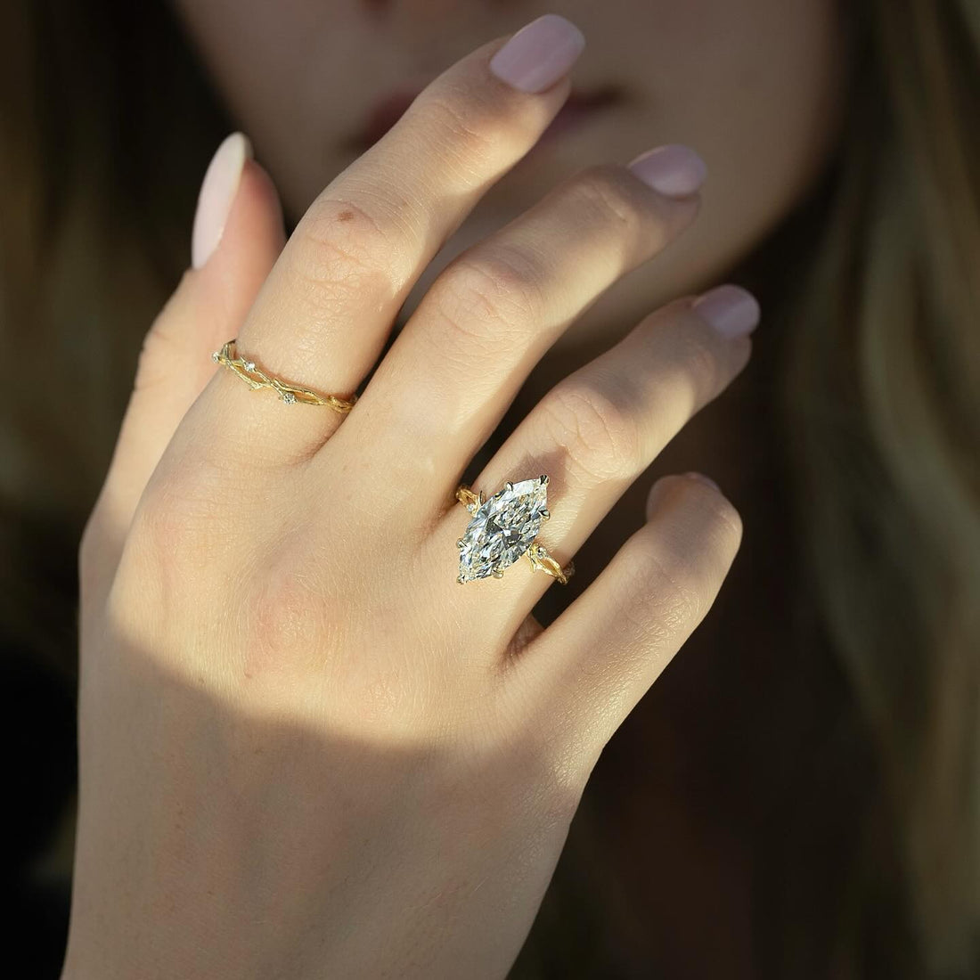 Marquise cut lab grown diamond solitaire ring on a carved branch band in yellow gold worn on the hand