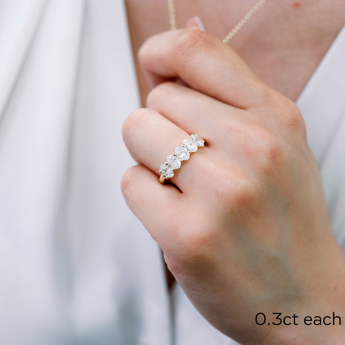 Oval moissanite five stone wedding band worn on the ring finger