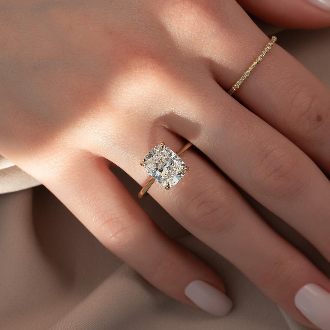 Cushion cut lab grown diamond ring with ultra slim shank in yellow gold worn on the hand