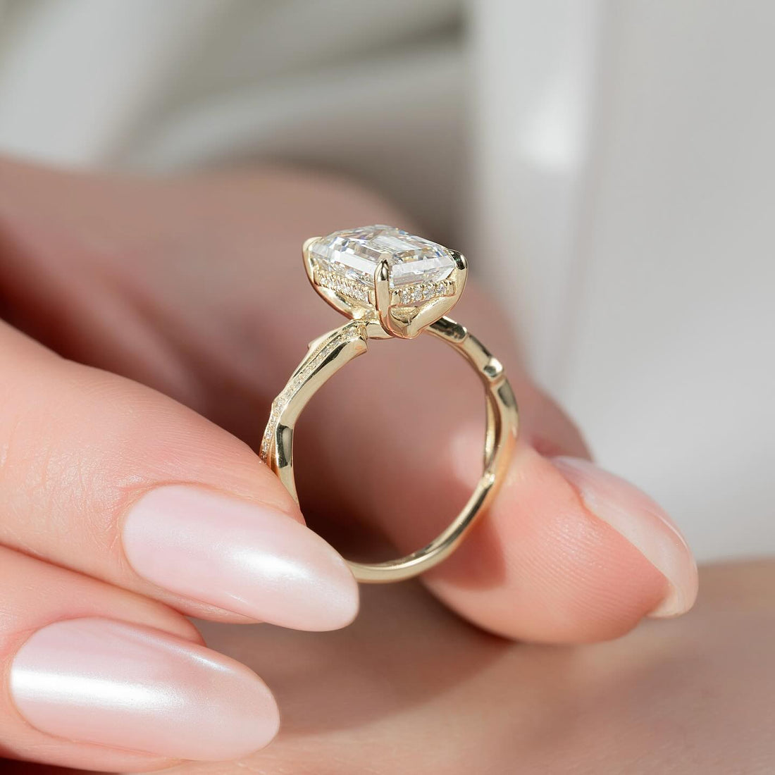Emerald cut lab grown diamond ring with hidden halo and knife edge pave band in yellow gold