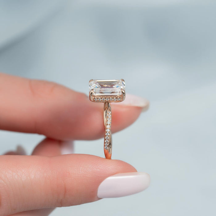 Profile showing the twisted pave shank and hidden halo under the emerald cut stone