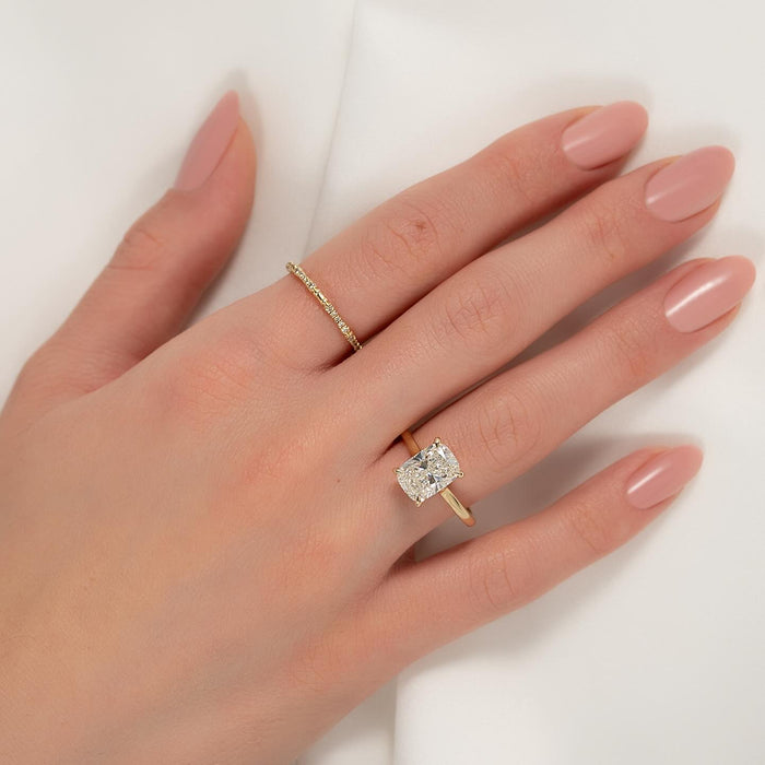 Elongated cushion lab grown diamond solitaire worn on the hand with a thin pave band