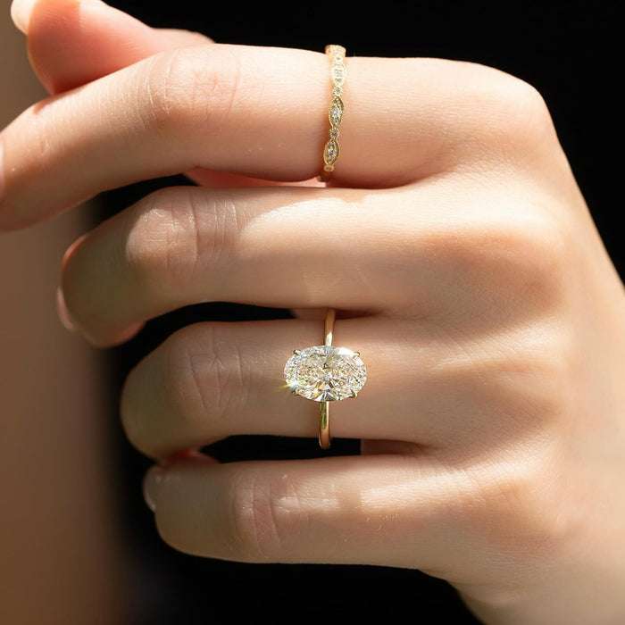 East west oval cut lab grown diamond solitaire ring in yellow gold worn on the hand