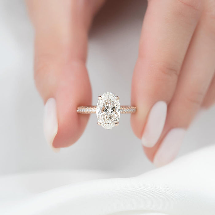 Oval lab grown diamond ring in rose gold with a concealed halo and pave band