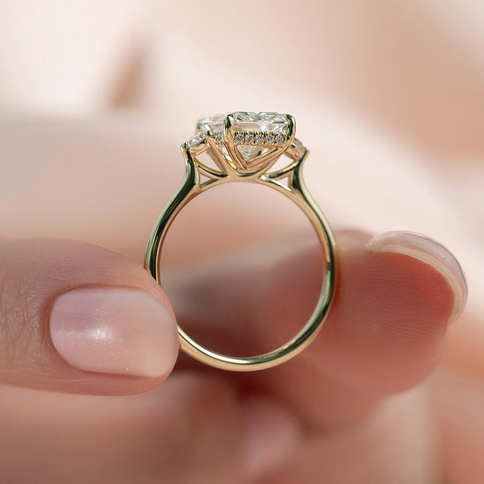 Round accent diamonds resting against each end of the radiant centre stone