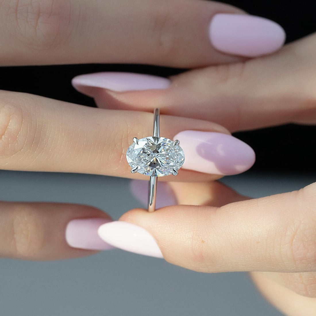 East west oval cut lab grown diamond ring with hidden halo on a plain white gold band