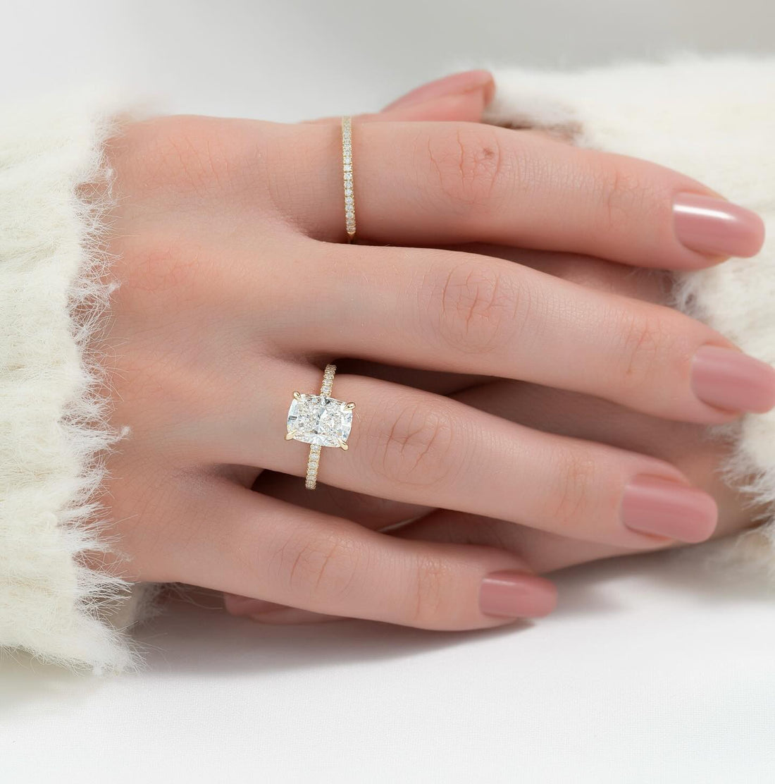 Elongated cushion cut lab grown diamond ring with pave shank in yellow gold worn on the hand