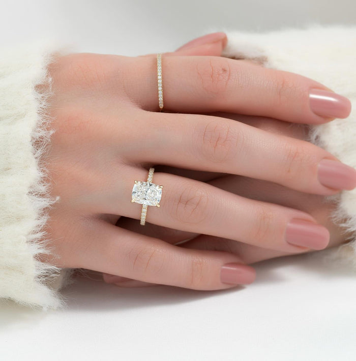 Elongated cushion cut lab grown diamond ring with pave shank in yellow gold worn on the hand