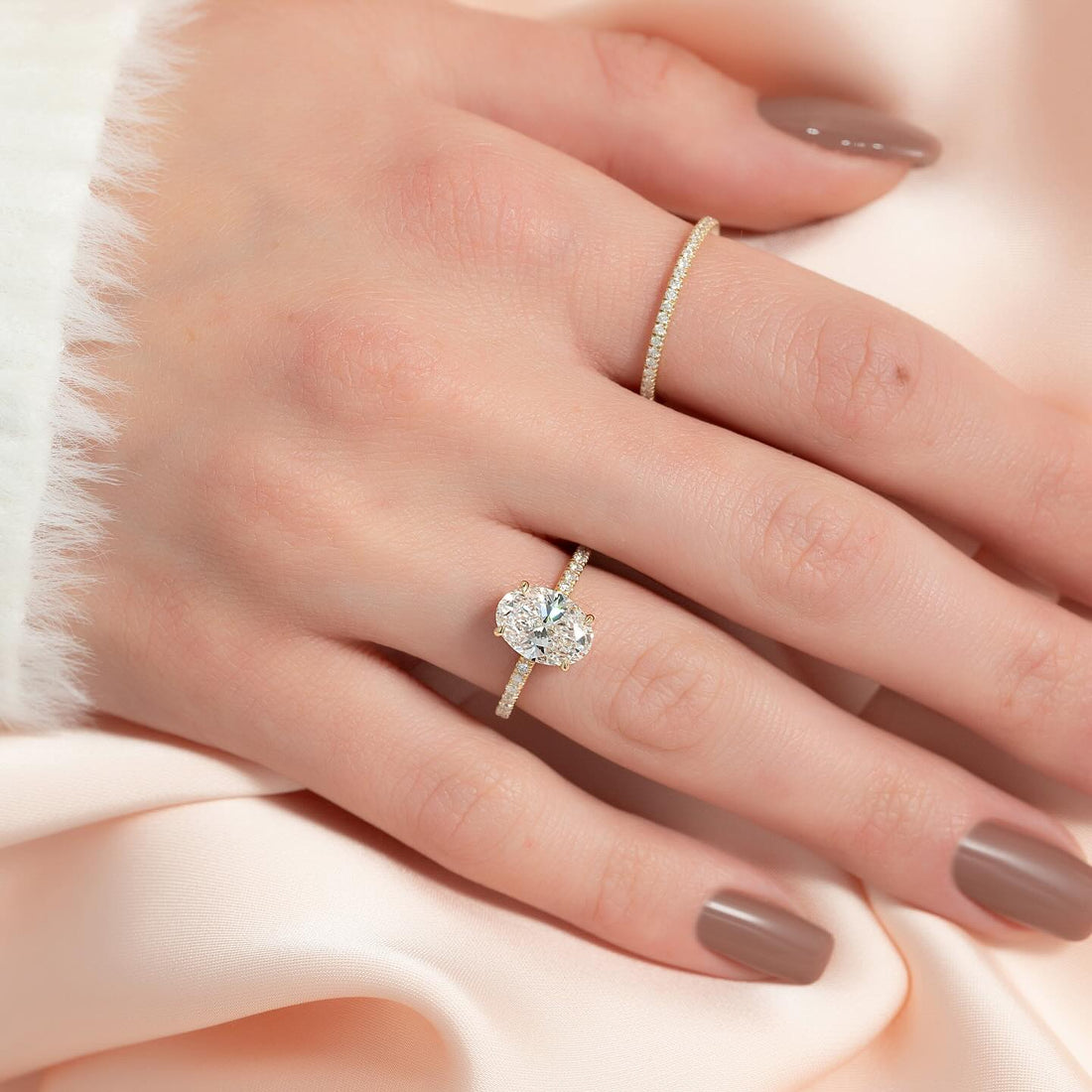 Oval cut lab grown diamond hidden halo ring with pave shoulders in yellow gold worn on the hand