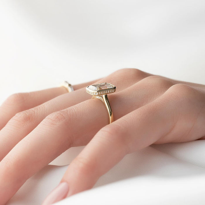 Emerald cut lab grown diamond bezel set ring in yellow gold showing the concealed halo in the bezel wall
