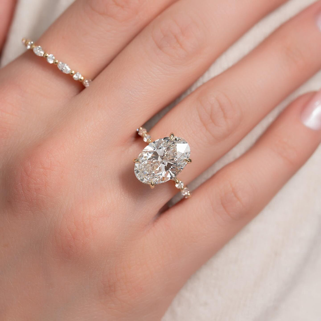 Oval cut lab grown diamond ring with graduated round accent shoulders in yellow gold