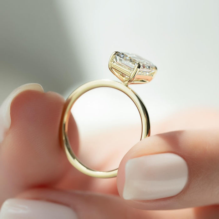 Profile of the east west emerald cut lab grown diamond ring on a flat yellow gold band