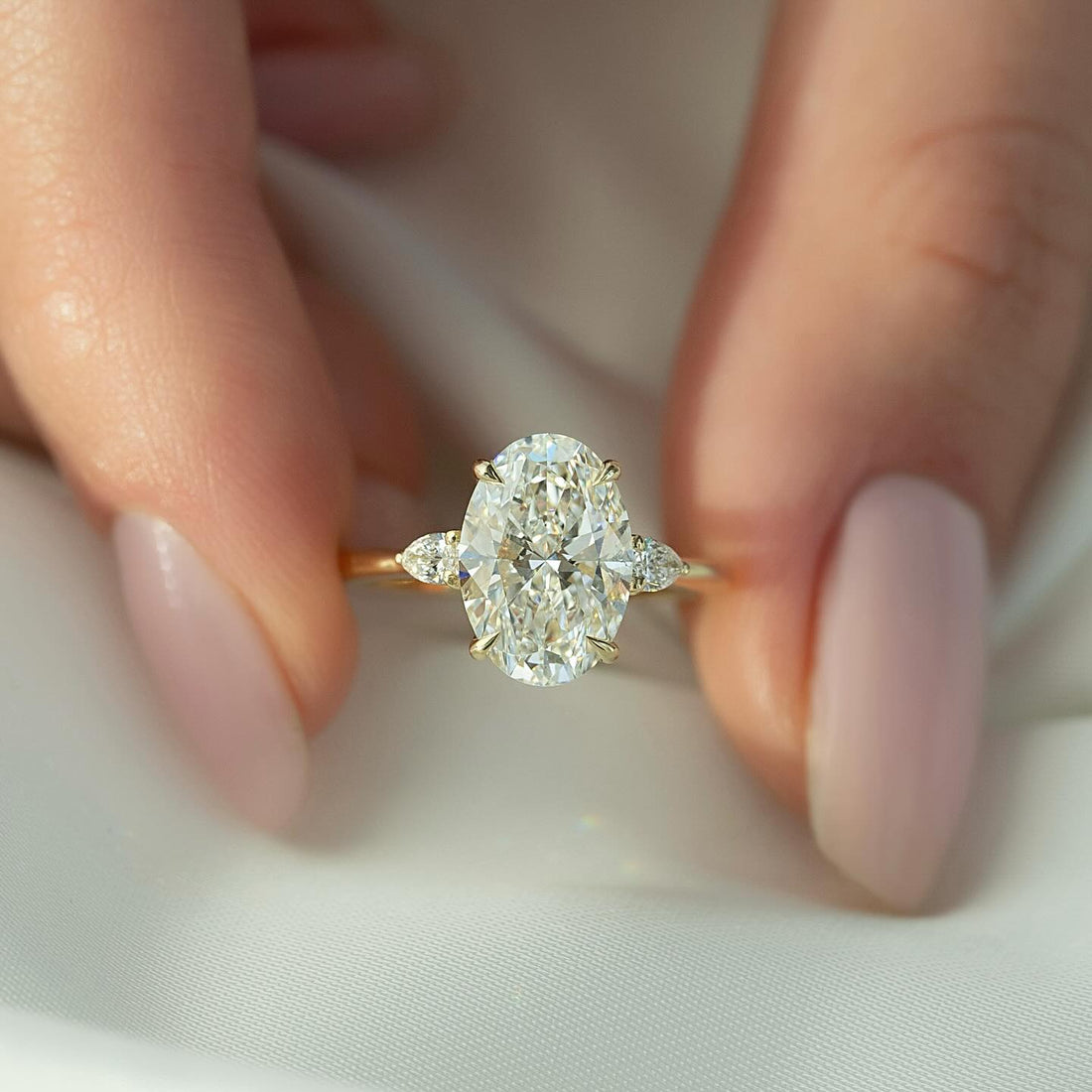 Oval cut lab grown diamond three stone ring with pear side stones in yellow gold