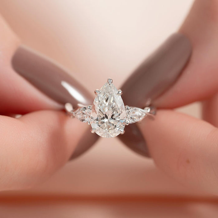 Two pear side diamonds angled outward beside the pear centre stone