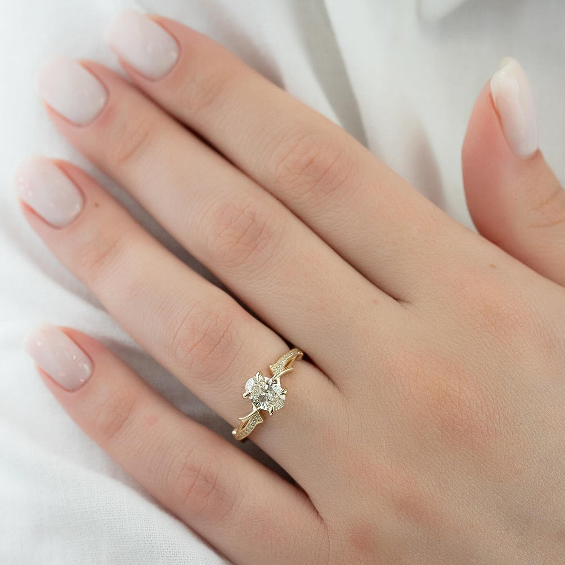 Oval cut lab grown diamond ring on a carved vine shank in yellow gold worn on the hand