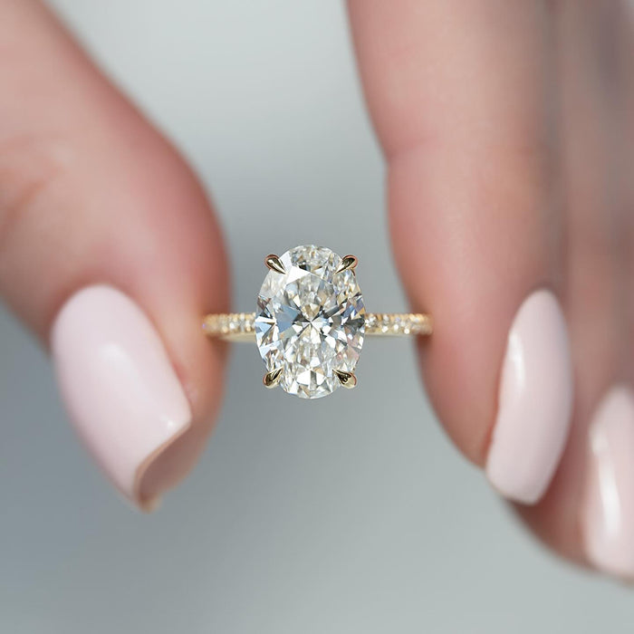 Oval lab grown diamond ring with a double concealed halo on a pave yellow gold band