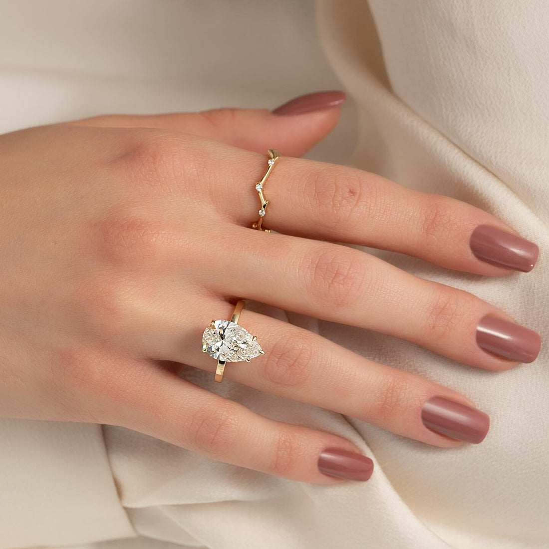 East west pear cut lab grown diamond solitaire in yellow gold worn on the hand
