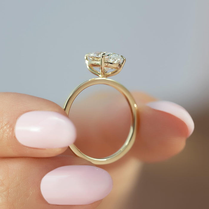 Side profile of the oval solitaire showing the open cross bar basket under the diamond