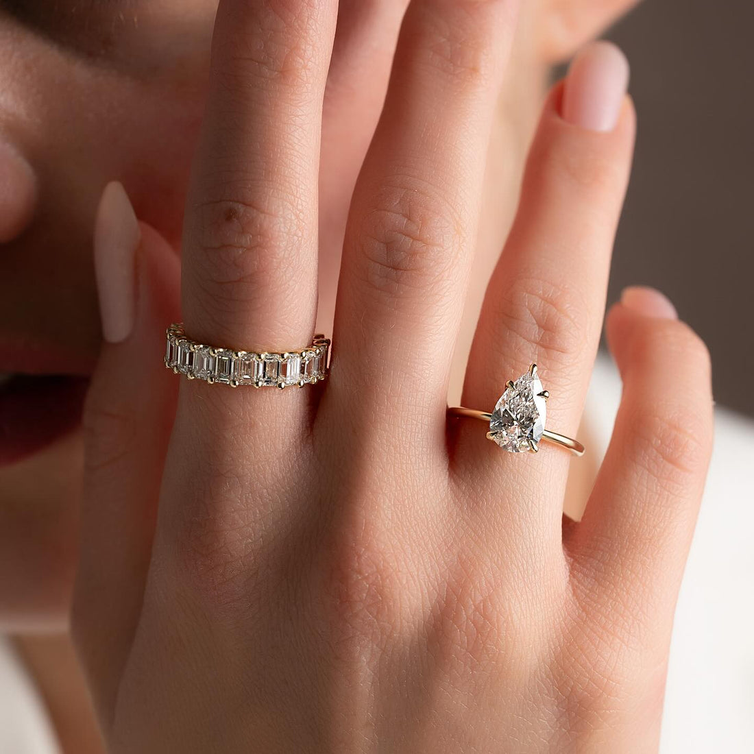 Pear cut lab grown diamond solitaire ring on a thin plain yellow gold band worn on the hand