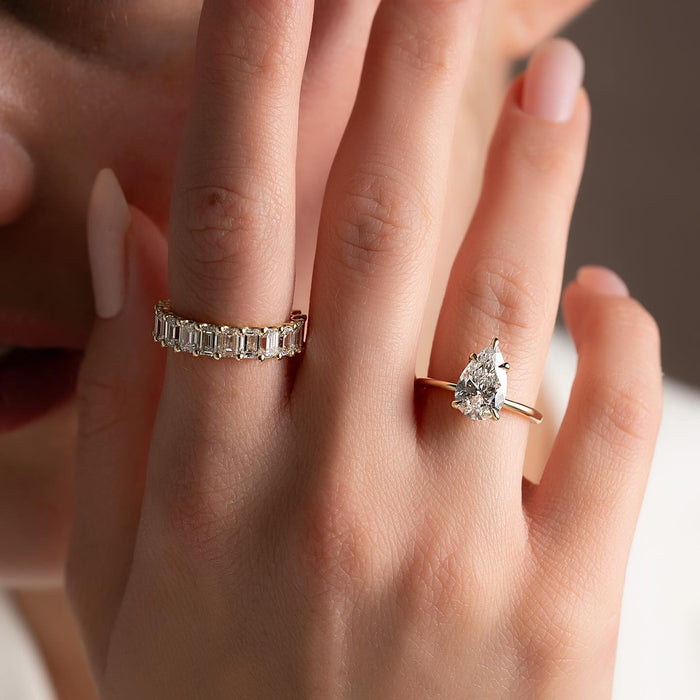 Pear cut lab grown diamond solitaire ring on a thin plain yellow gold band worn on the hand
