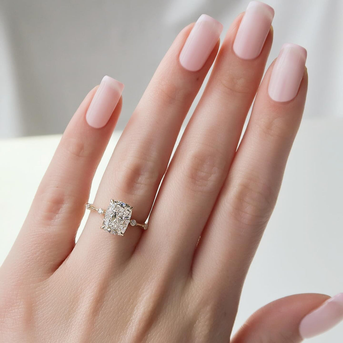 Elongated cushion cut lab grown diamond ring on a whisper thin band worn on the hand