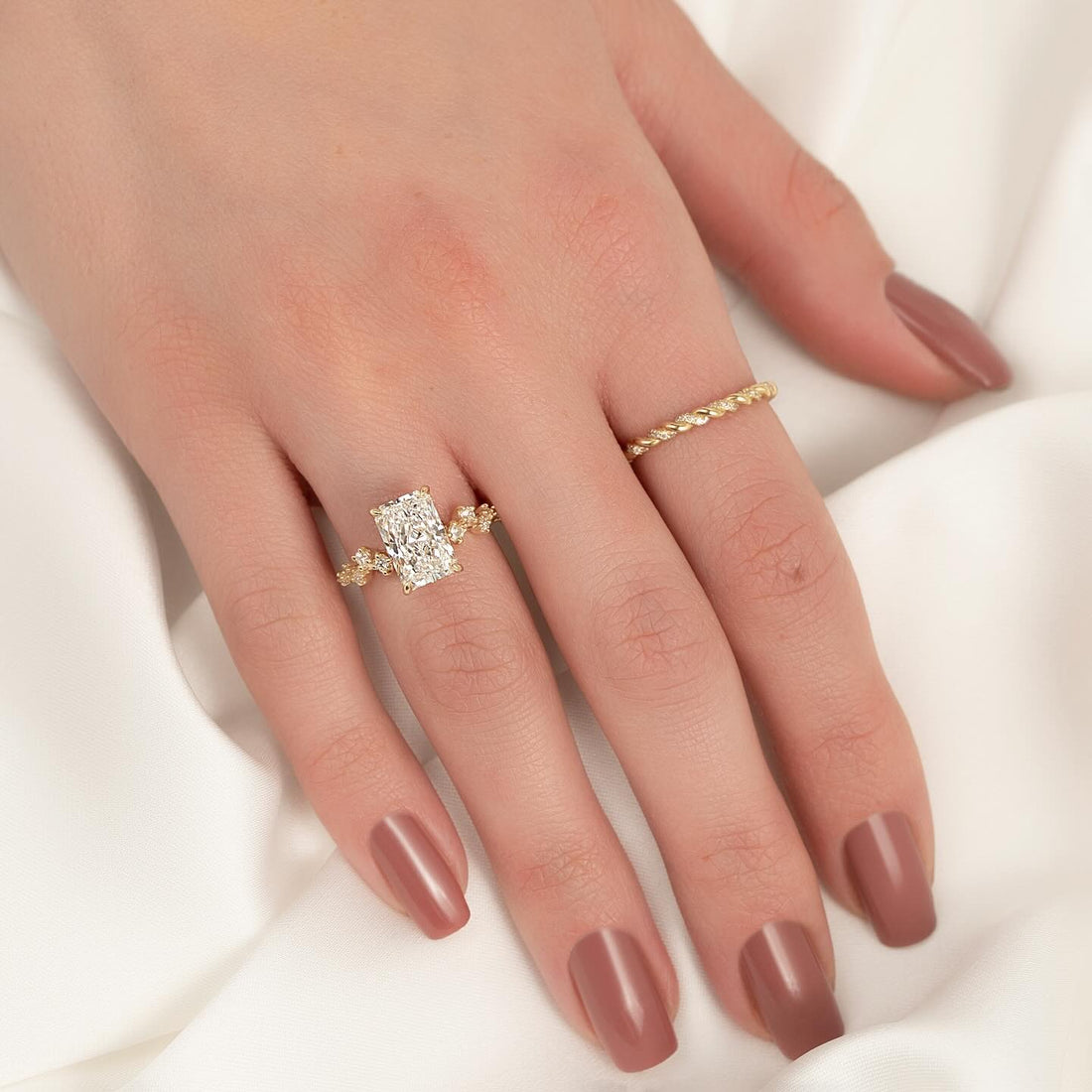 Elongated radiant cut lab grown diamond ring with cluster shoulders in yellow gold worn on the hand